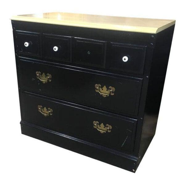 Black dresser with four drawers and gold handles.