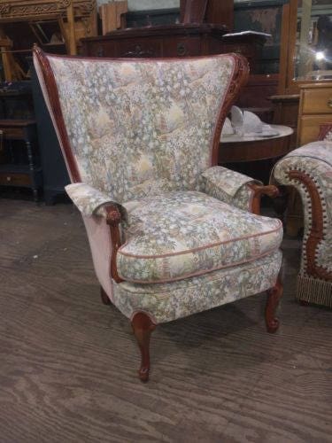 Floral patterned wingback armchair with wood legs.